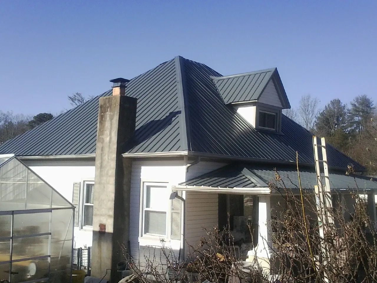 Dark blue standing seam metal roof on a white farmhouse with dormer — Slate & Tile Roof Repair by Roofing Brothers in Camden