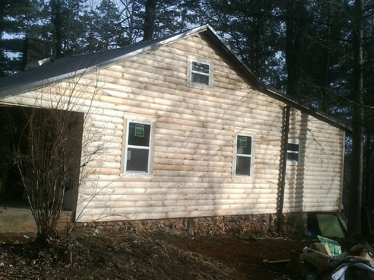 New log siding and dark metal roofing on a gable end in Camden