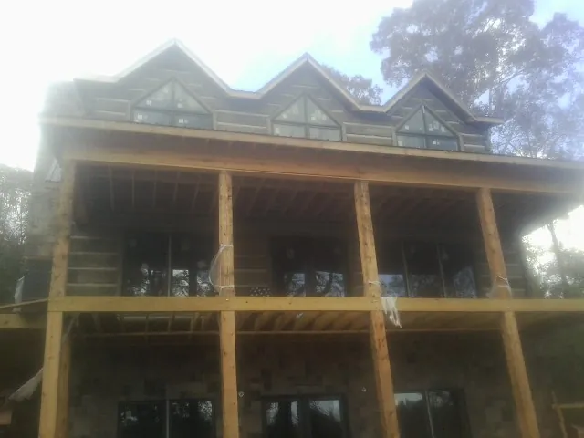 Dormers and porch framing on a large log home under construction — Roof Coating work by our crew in Camden