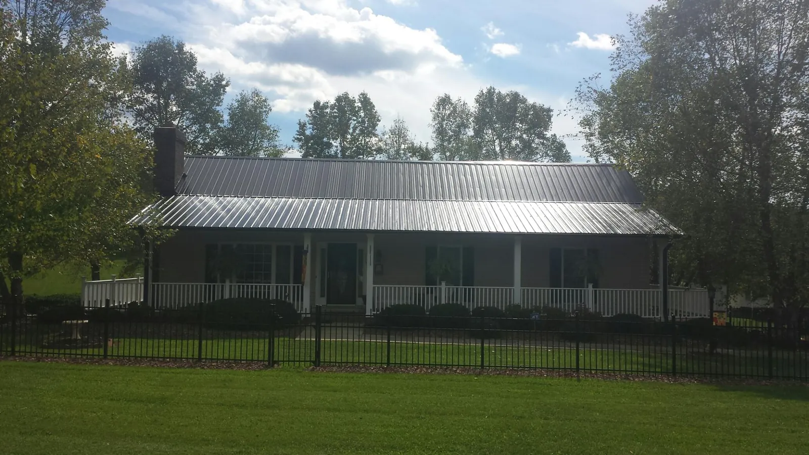 Gray metal roof on a brick ranch with a full width front porch — Gutter Guard Installation work by our crew in Camden